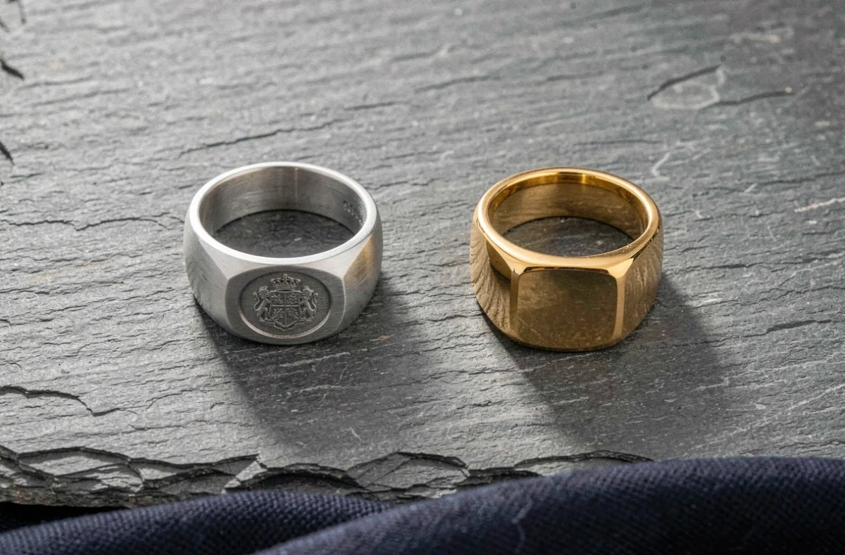 Comparaison entre une chevalière en argent et une chevalière en or jaune posées sur une ardoise grise