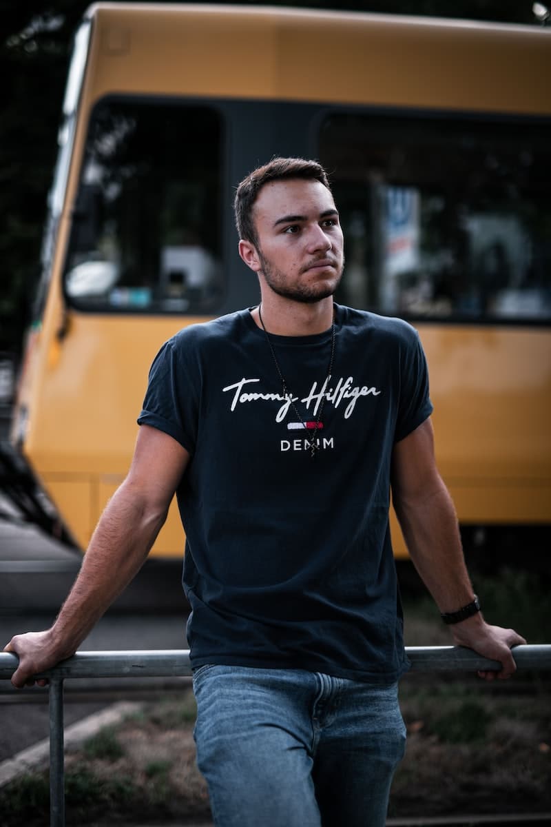 man in gray crew neck t-shirt standing beside yellow bus during daytime